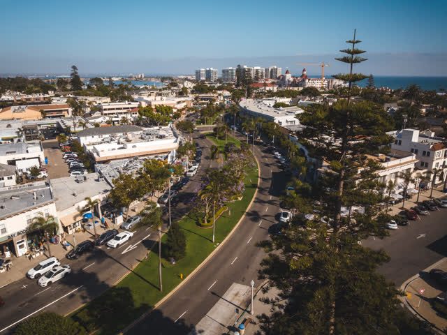 Aerial view of the downtown streets, palm trees and the ocean in Coronado, with people walking.