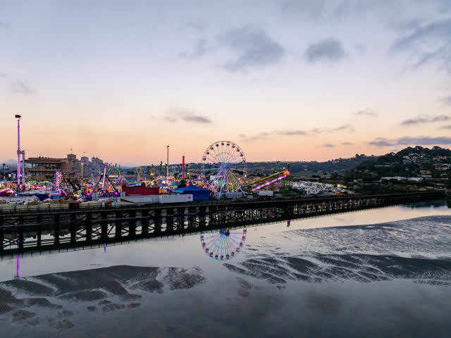Low aerial view of the beach, open country and the water in Del Mar, with a crowd gathered.