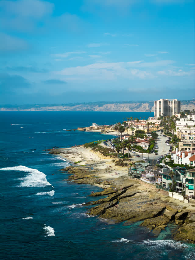 Aerial view of the cliffs, the surf and palm trees at La Jolla Cove.