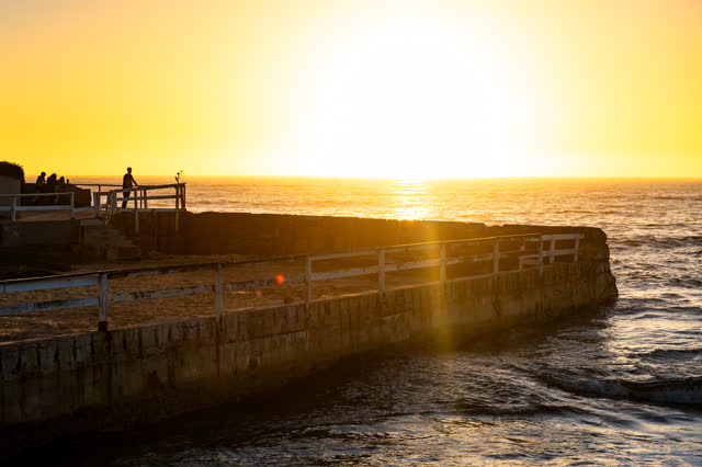 The beach, the pier and the ocean in Ocean Beach, with people walking.