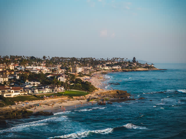 Aerial view of the beach, the surf and palm trees at Windansea, with people walking.