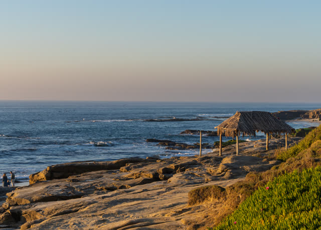 Elevated view of the cliffs, the ocean and open country at Windansea, with people walking.