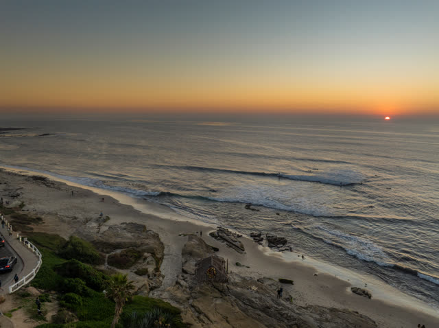 Aerial view of the beach, the surf and palm trees at Windansea, with surfers out.