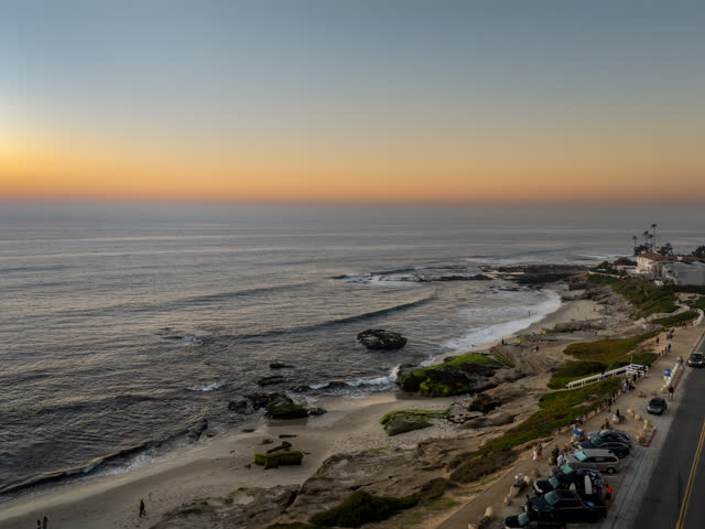 Aerial view of the cliffs, the ocean and homes at Windansea, with people walking.