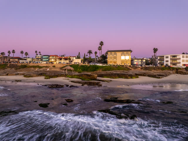Low aerial view of the beach, the surf and palm trees at Windansea.