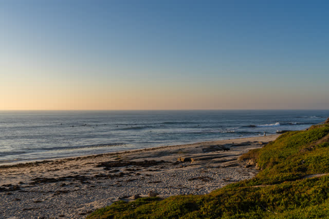 Elevated view of the beach, the surf and the ocean at Windansea, with surfers out.