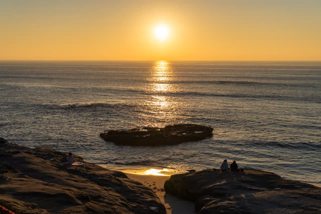 Elevated view of the cliffs, the ocean and the beach at Windansea, with people walking.