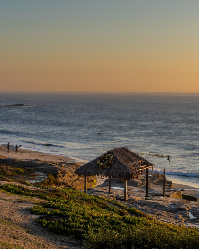 Elevated view of the cliffs, the surf and the ocean at Windansea, with people walking.