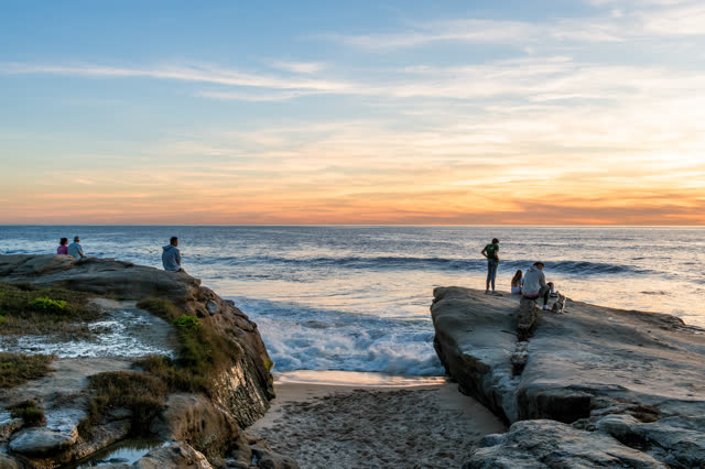 Elevated view of the cliffs, the ocean and open country at Windansea, with a crowd gathered.