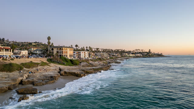Aerial view of the cliffs, the surf and palm trees at Windansea, with people walking.