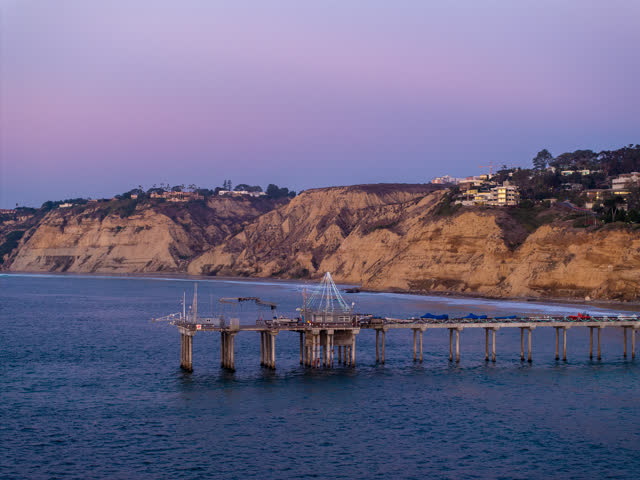 Low aerial view of the cliffs, the pier and the ocean at La Jolla Shores.