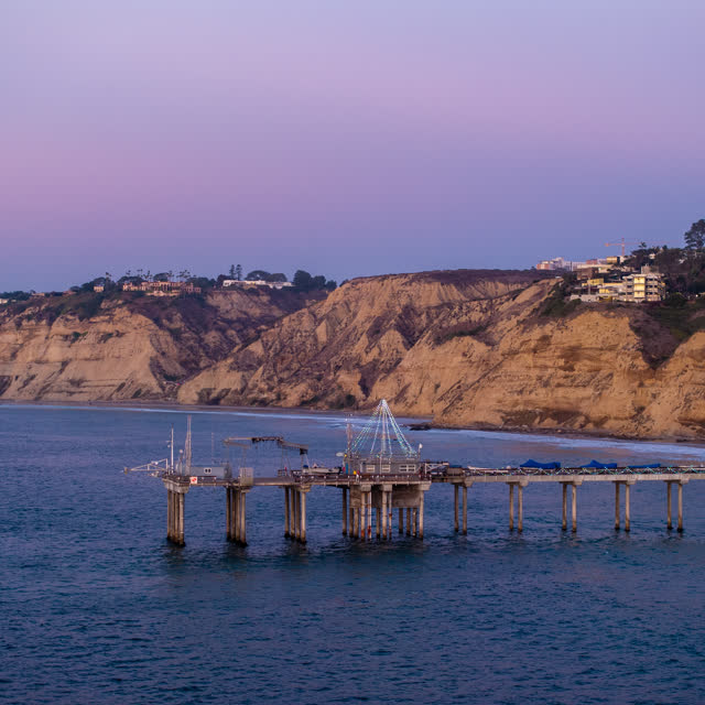 Low aerial view of the cliffs, the pier and the ocean at La Jolla Shores.