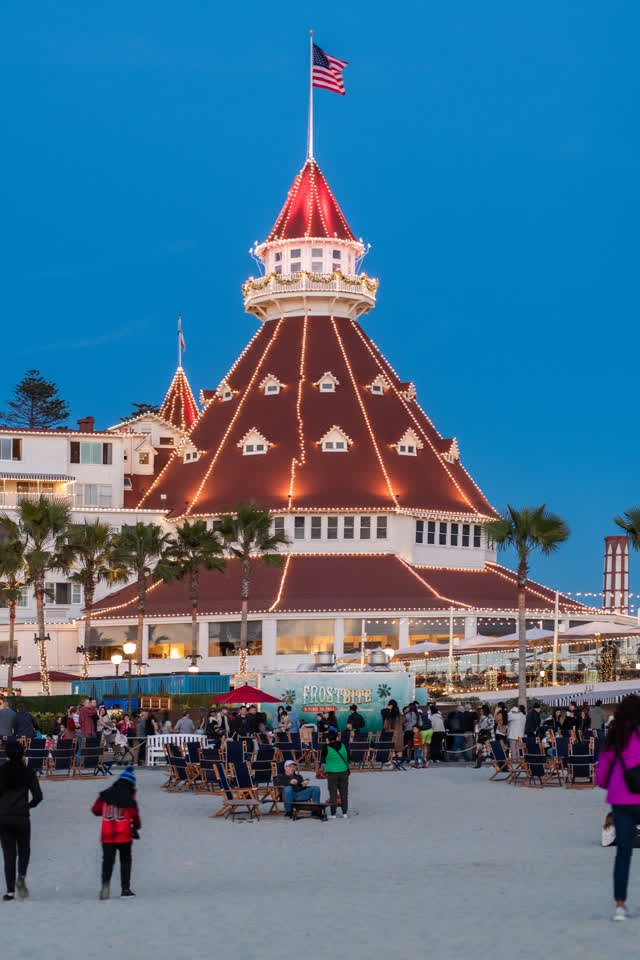 The beach, palm trees and the buildings at Coronado Beach, with a crowd gathered.