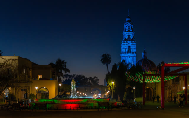 A park, palm trees and the buildings in Balboa Park, with a crowd gathered.