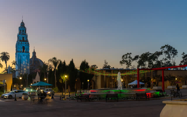 A park, palm trees and the buildings in Balboa Park, with a crowd gathered.