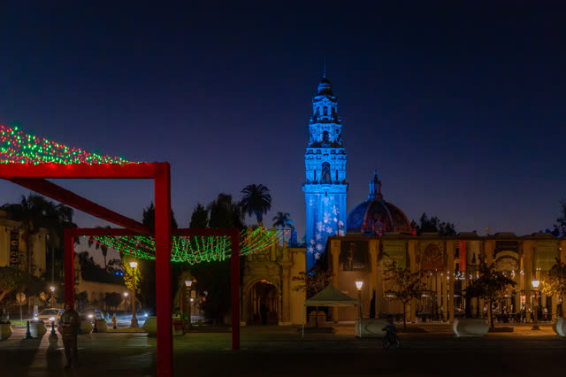 A park, palm trees and the buildings in Balboa Park, with a crowd gathered.
