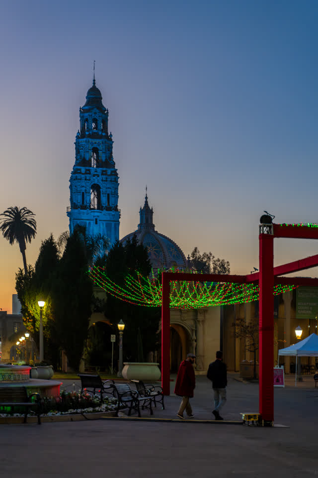 A park, palm trees and the buildings in Balboa Park, with people walking.
