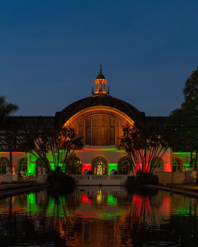 A park, palm trees and the buildings in Balboa Park, with a crowd gathered.