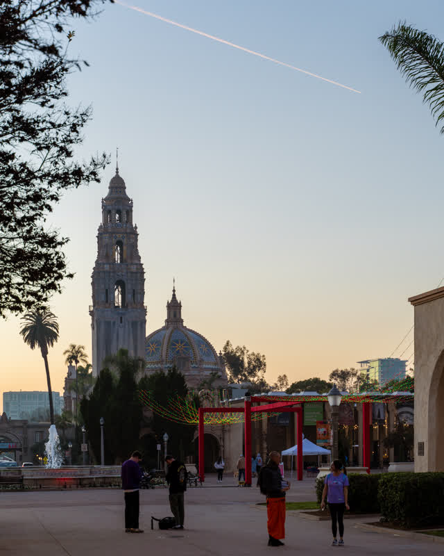 A park, palm trees and the buildings in Balboa Park, with people walking.