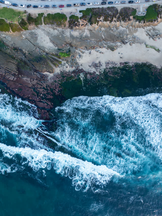 Aerial view of the cliffs, the surf and the ocean at La Jolla Cove.