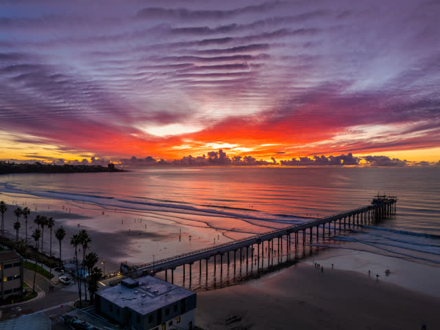 Overhead drone photo of Scripps Pier during sunset in La Jolla Shores San Diego California highlighting ocean texture and glowing horizon | Drone Photo – 10