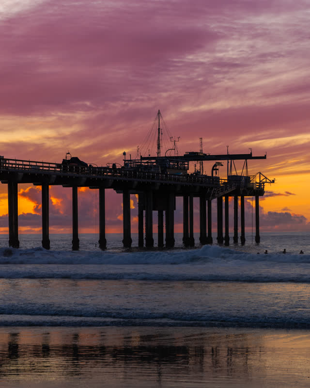 View from the water of the beach, the surf and the pier at La Jolla Shores, with swimmers in the water.
