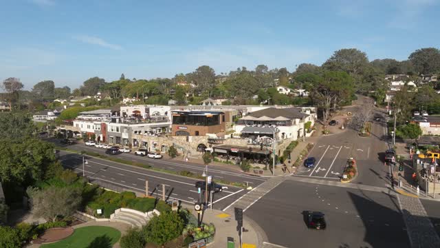 Low aerial view of the downtown streets, palm trees and homes in Del Mar, with people walking.
