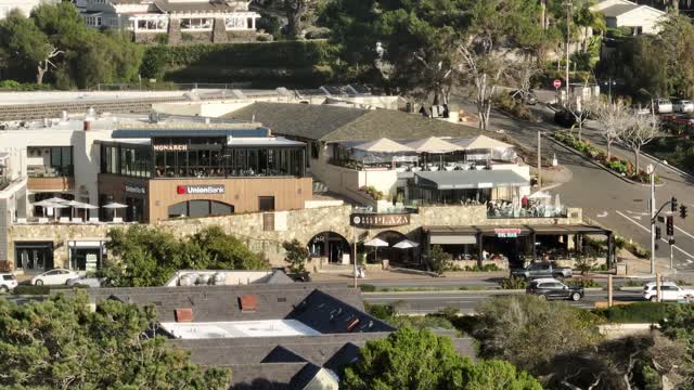 Low aerial view of the downtown streets, homes and the buildings in Del Mar, with people eating outside.