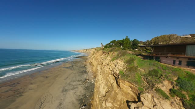 Low aerial view of the cliffs, the surf and the ocean at La Jolla Shores.