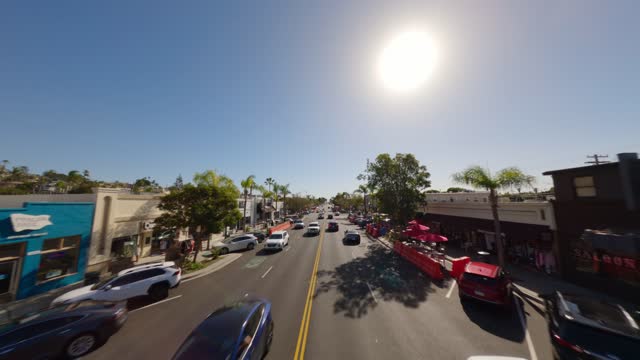 Low aerial view of the downtown streets, palm trees and the buildings at Downtown Encinitas, with people walking.