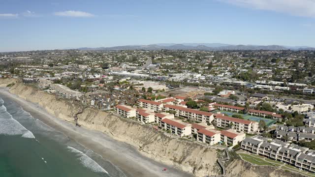 Aerial view of the cliffs, the surf and the ocean in Solana Beach, with people walking.