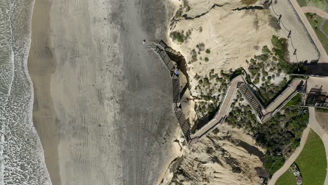 Aerial view of the beach, the surf and the ocean in Solana Beach, with people walking.