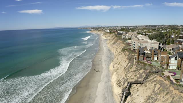 Aerial view of the cliffs, the surf and the ocean in Solana Beach, with people walking.