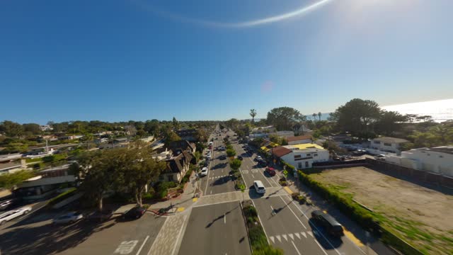 Low aerial view of the downtown streets, the ocean and homes in Del Mar, with people walking.