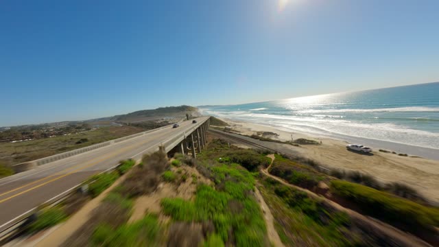 Low aerial view of the beach, the surf and the bridge at Torrey Pines.