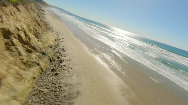 Low aerial view of the beach, the surf and the ocean at Torrey Pines.