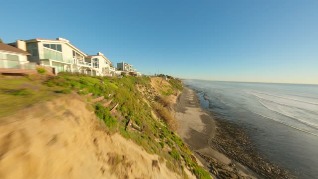 Low aerial view of the cliffs, the surf and the ocean at Leucadia.