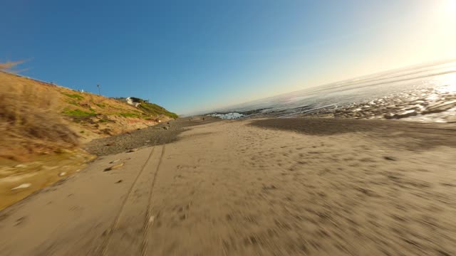 Low aerial view of the beach, the surf and the ocean at Leucadia, with people walking.