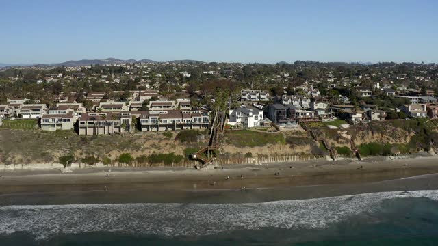 Aerial view of a residential street, the ocean and homes at Leucadia, with people walking.