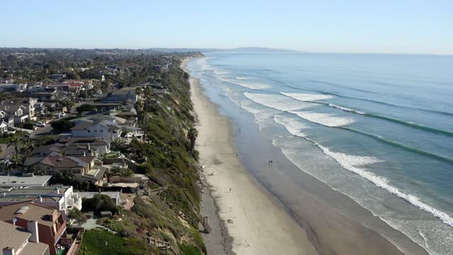 Aerial view of the beach, the surf and palm trees at Leucadia, with people walking.