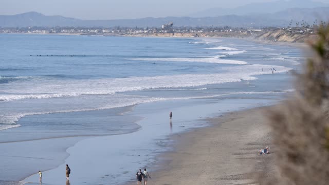 Elevated view of the beach, the surf and the ocean at Leucadia, with people walking.