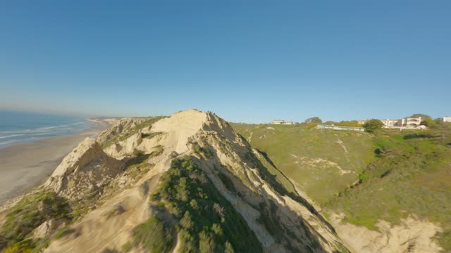 Low aerial view of the cliffs, the ocean and homes at Black’s Beach.