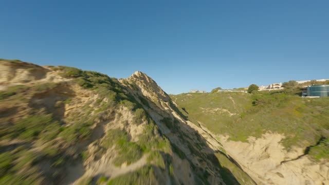 Low aerial view of the cliffs, homes and open country at Black’s Beach.