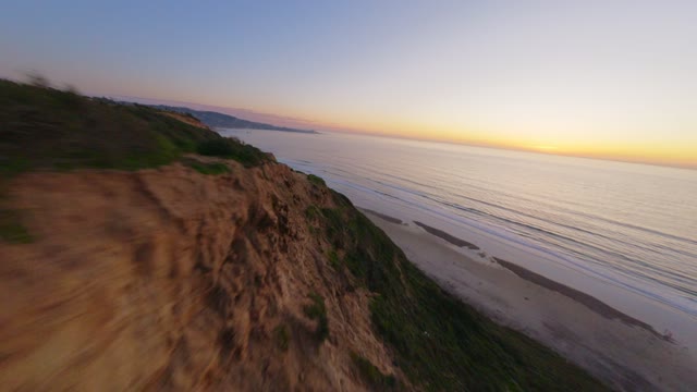 Low aerial view of the cliffs, the ocean and the beach at Black’s Beach.