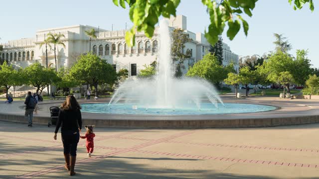 A park, palm trees and the buildings in Balboa Park, with people walking.