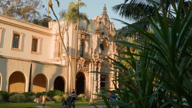 A park, palm trees and the buildings in Balboa Park, with people walking.