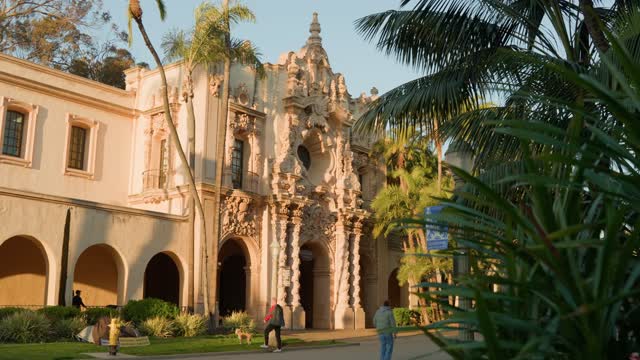 A park, palm trees and the buildings in Balboa Park, with people walking.