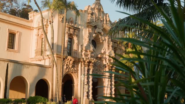 A park, palm trees and the buildings in Balboa Park, with people walking.