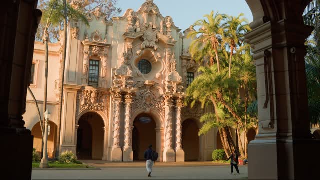 A park, palm trees and the buildings in Balboa Park, with people walking.