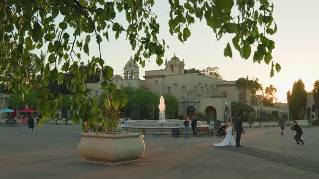 A park, palm trees and the buildings in Balboa Park, with a crowd gathered.